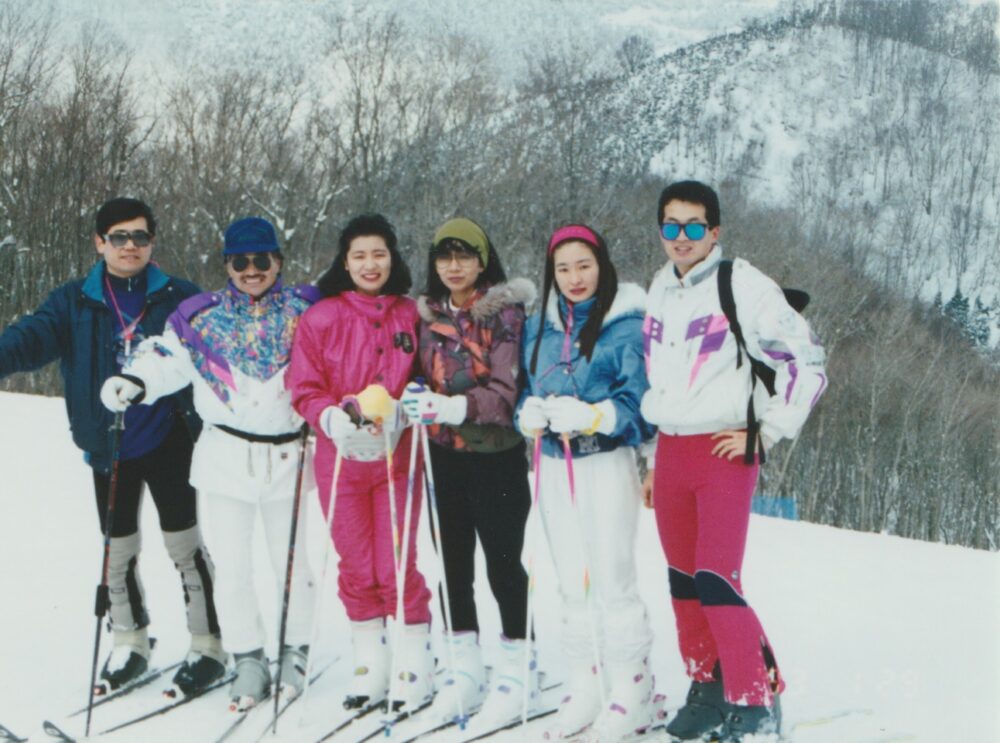 雪が積もった山で、仲間たちとスキーウェアを身に付けて集合写真